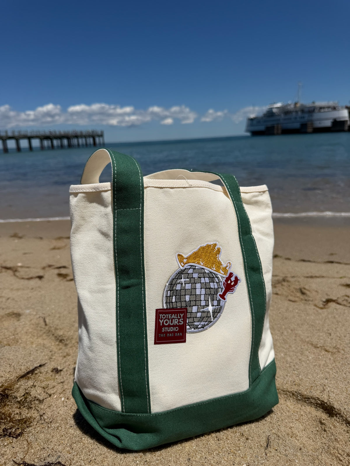 Green beach tote with disco ball, lobster, and crown patches